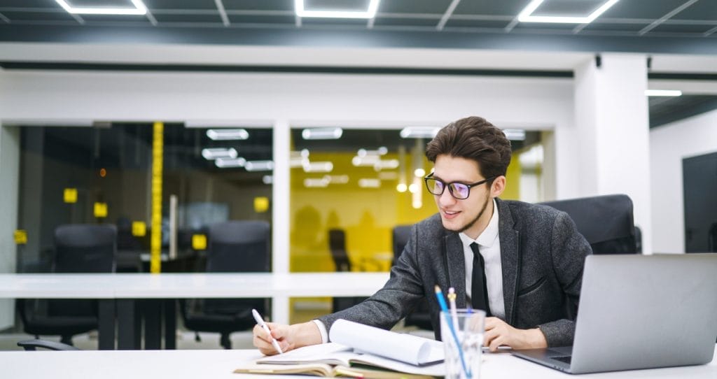 Young office manager working with papers and computer working at office. Man in a suit working. | Quantitative and Qualitative Research