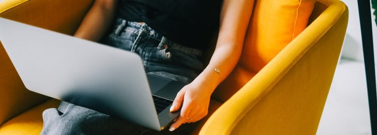 Young woman sitting in a yellow chair on her laptop | Should you hire a freelance web developer?