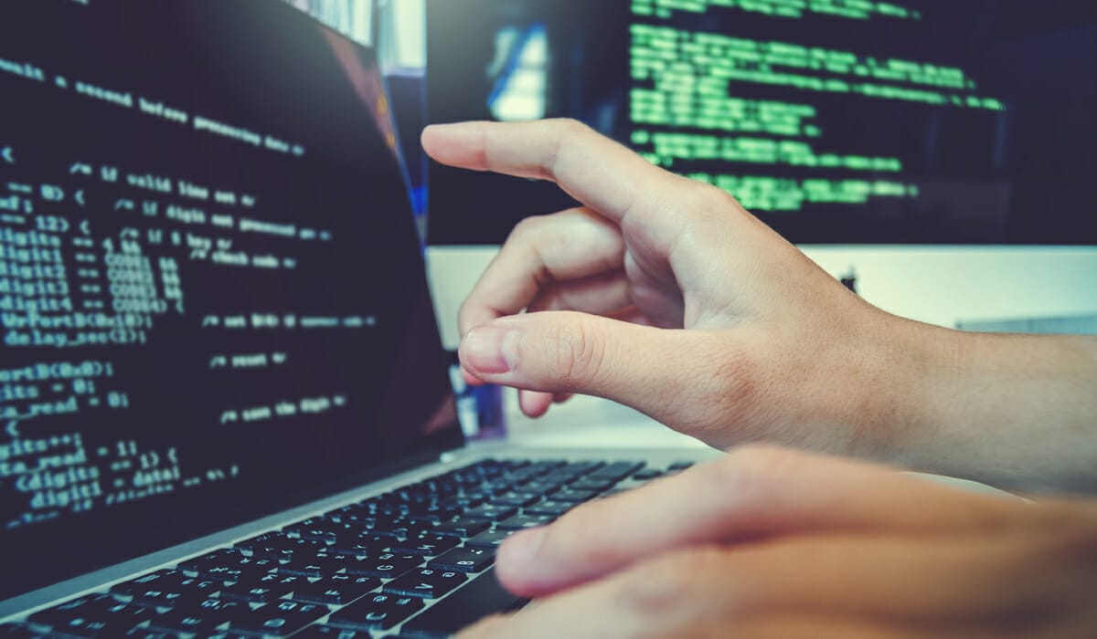 Person points at screen filled with web development coding
