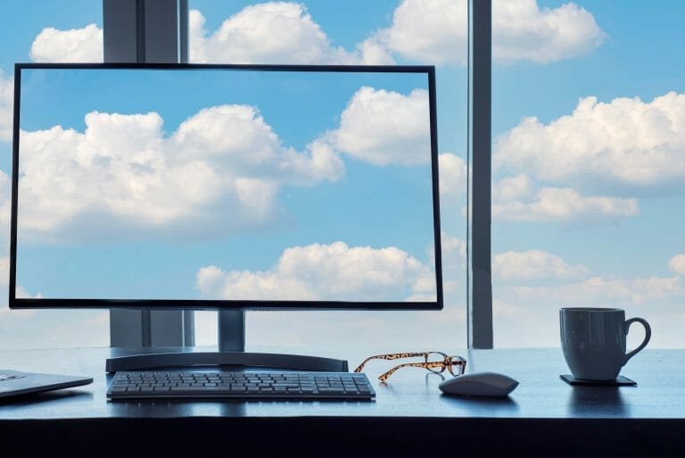 Benefits of Cloud Computing | Screen and windows with blue sky clouds from office desk.